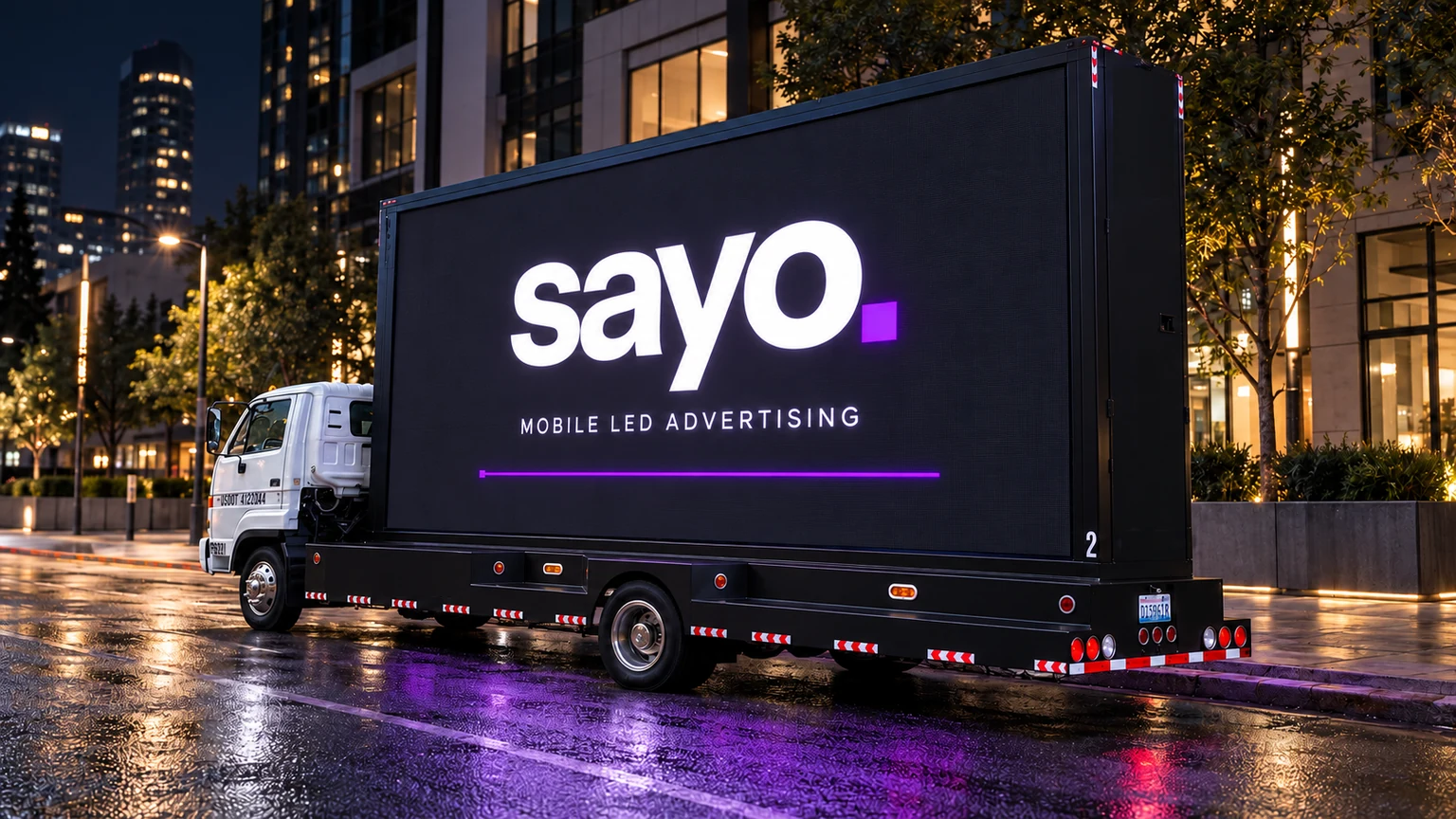 Sayo’s white-cab LED truck, its screen lit on a wet city street at night. Campaign visualization.